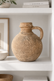 Aged brown decorative jug styled on a white built-in shelf.