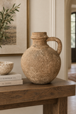 Aged brown decorative jug styled on a wood entryway console.