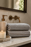 Brown and white striped bath towel folded on a marble bathroom countertop.