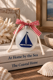 Frosted glass sailboat holiday ornament with gingham ribbon and off-white nautical rope