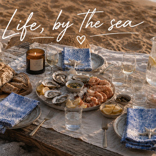Life, by the sea: beach picnic table with a seafood platter, blue napkins and a candle