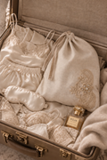 French linen and brocante lace lingerie bag in natural linen, crystals on floral motif, staged in an elegant travel suitcase