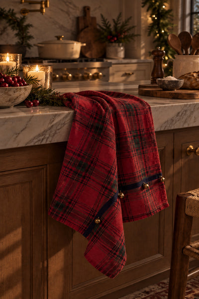 Red tartan holiday kitchen towel with three sewn bells styled in a warm Christmas kitchen