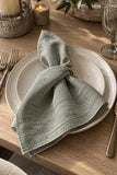 Mayenne Maison sage-gray dinner napkin styled on a plate, sold as a set of four