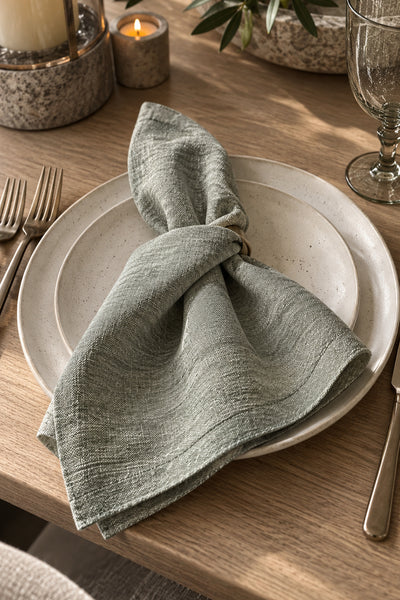 Mayenne Maison sage-gray dinner napkin styled on a plate, sold as a set of four