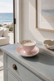 Pink rose china teacup and saucer soy candle styled on a coastal console