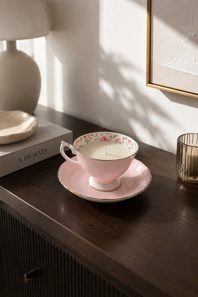 Pink rose china teacup and saucer soy candle styled on a dark wood console